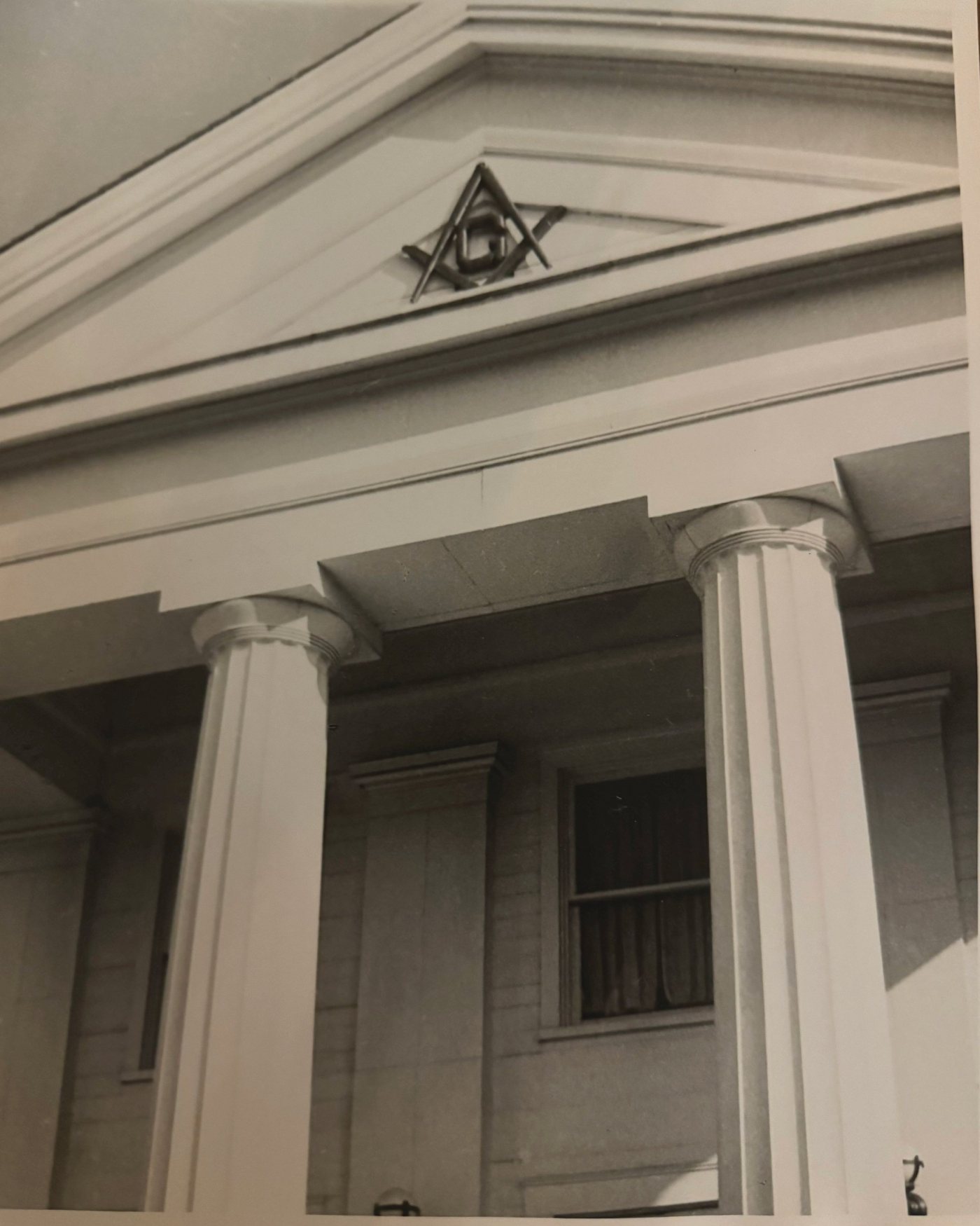 Archival photograph of the Lodge pediment and Doric columns with the square-and-compasses emblem