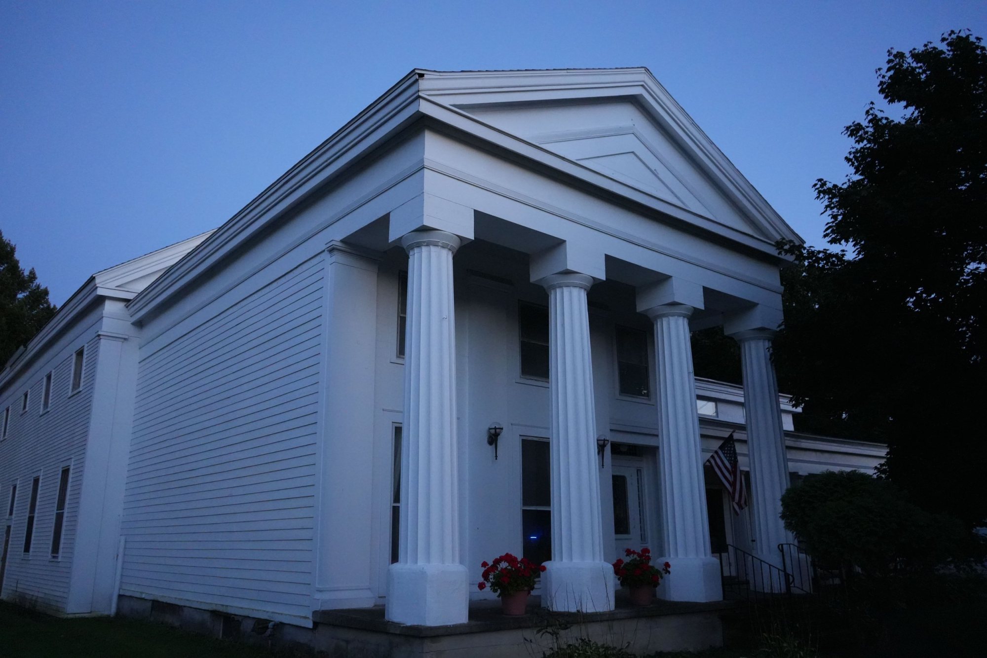 The Tully Masonic Lodge at dusk, white columns against a darkening sky